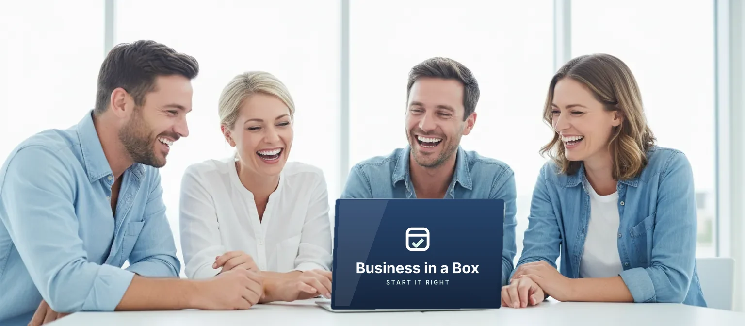 Two men and two women laughing together over a Business in a Box laptop at a meeting table